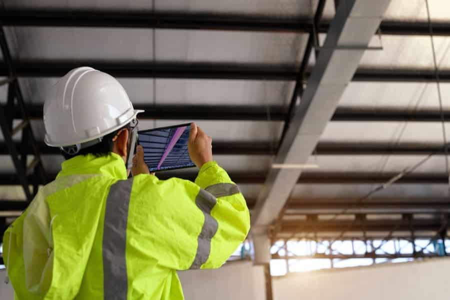 ouvrier sur un chantier qui fait une vérification des infrastructures avec une tablette